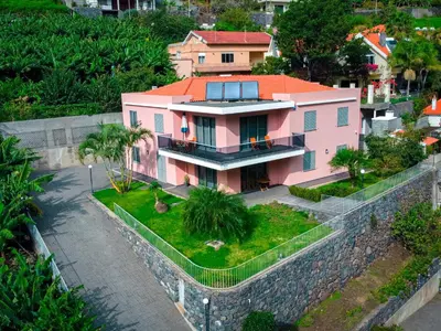 a pink house on top of a stone wall at Quinta das Rosas in Ribeira Brava