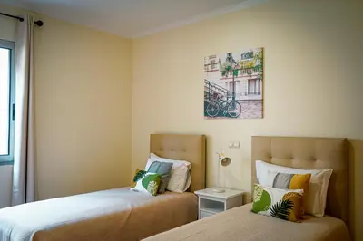 a bedroom with two beds and a picture on the wall at Quinta das Rosas in Ribeira Brava