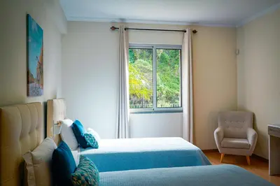a bedroom with a bed and a window and a chair at Quinta das Rosas in Ribeira Brava