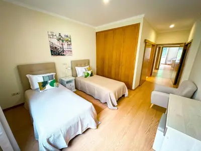 a hotel room with two beds and a chair at Quinta das Rosas in Ribeira Brava