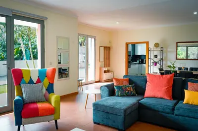 a living room with a blue couch and colorful pillows at Quinta das Rosas in Ribeira Brava