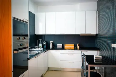 a white kitchen with white cabinets and a table at Quinta das Rosas in Ribeira Brava