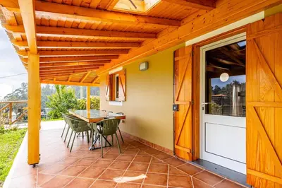 a patio with a table and chairs and a glass door at Recanto do Pomar - Three bedroom villa in Ponta do Sol