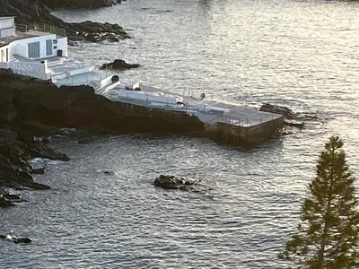 a dock in a body of water with a house at Апартаменты 303 - Studio in Funchal