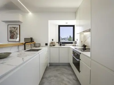 a white kitchen with white cabinets and a window at Baía Beach Apartment in Luz