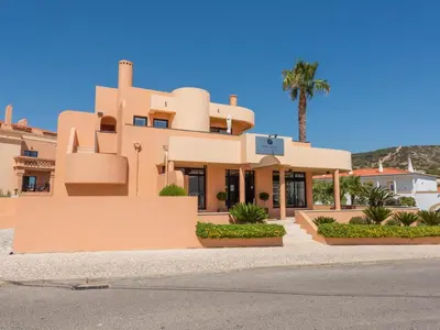 a building with a palm tree in front of it at Baía Beach Apartment in Luz