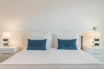 a bedroom with a white bed with blue pillows at Madalenas II by An Island Apart in Funchal