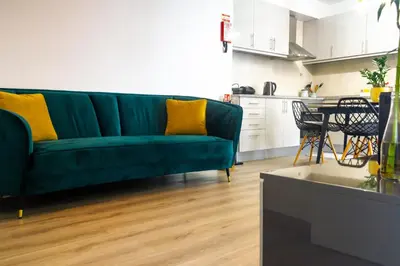a living room with a green couch and a kitchen at Faria House by Horizon View Madeira in Funchal