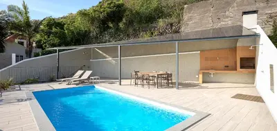 a house with a swimming pool and a table and chairs at Marco 4 Seasons- Summer in Arco da Calheta