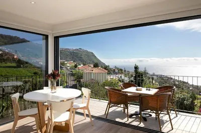a balcony with tables and chairs and a view of the ocean at Marco 4 Seasons- Summer in Arco da Calheta