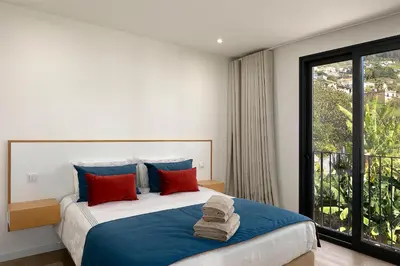 a bedroom with a large bed with blue and red pillows at Marco 4 Seasons- Summer in Arco da Calheta