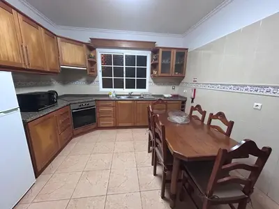 a kitchen with a wooden table and wooden cabinets at Vila Mendes - Ocean View in Arco da Calheta