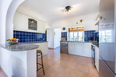 a kitchen with white cabinets and blue tiles at Casa Cool in Aljezur