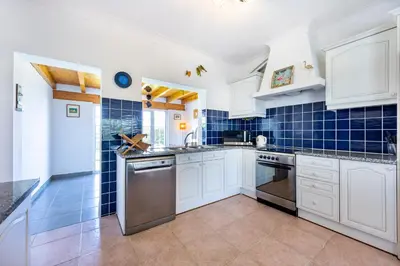 a kitchen with white cabinets and blue tiles at Casa Cool in Aljezur