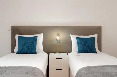 two beds with blue pillows in a bedroom at Caniço Golden by An Island Apart in Caniço