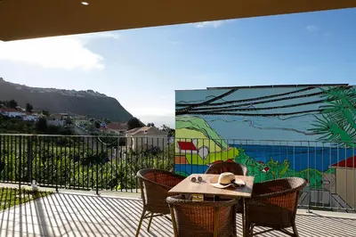 a table and chairs on a balcony with a mural at Marco 4 Seasons- Winter in Arco da Calheta