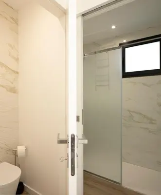 a bathroom with a toilet and a glass shower door at Marco 4 Seasons- Winter in Arco da Calheta