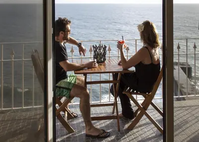 a man and woman sitting at a table on a balcony at One Love Maktub in Paul do Mar