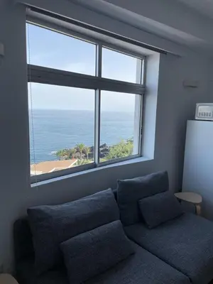 a living room with a couch and a large window at Ocean View Studio 2 with pool in Funchal