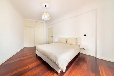 a white bedroom with a large bed and wooden floors at Home in Funchal in Funchal