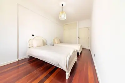 two beds in a white bedroom with wood floors at Home in Funchal in Funchal