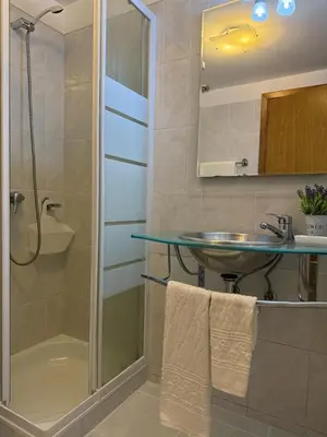 a bathroom with a sink and a shower with a glass counter at BelleMar Vacations in Funchal