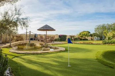 a golf course with a putting green with an umbrella at Spacious villa with sea view, tennis & golf garden #1963 in Alagoas