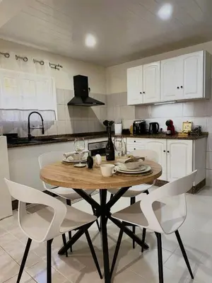 a kitchen with a wooden table and white chairs at Dani House - Porto Moniz Escape in Porto Moniz