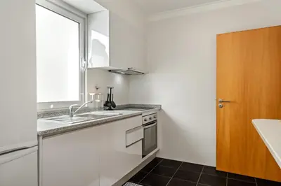 a white kitchen with a sink and a window at Sunflower Living by Homie in Caniço