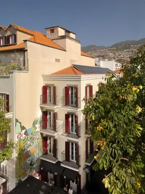 an apartment building with red shutters and a tree at Safira Suites 202 in Funchal