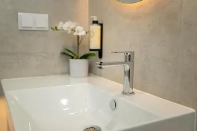 a white sink with a faucet and a vase of flowers at Safira Suites 301 in Funchal