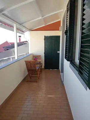a balcony with two chairs and a green door at Casa Ponte in Ponta do Sol