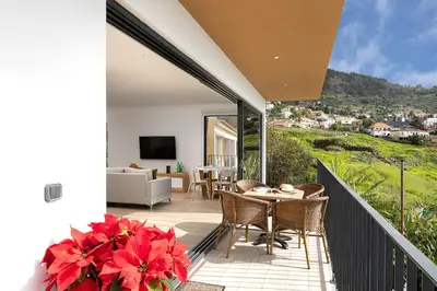 a patio with a table and chairs on a balcony at Marco 4 Seasons- Autumn in Arco da Calheta