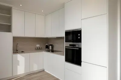 a kitchen with white cabinets and black appliances at Marco 4 Seasons- Autumn in Arco da Calheta