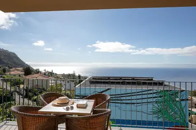 a table and chairs on a balcony overlooking the ocean at Marco 4 Seasons- Autumn in Arco da Calheta