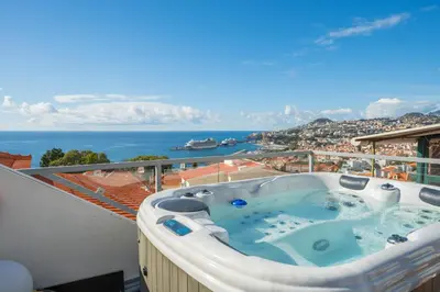 a hot tub on a balcony with a view of the ocean at FLH Funchal Sissi Lanço with View in Funchal
