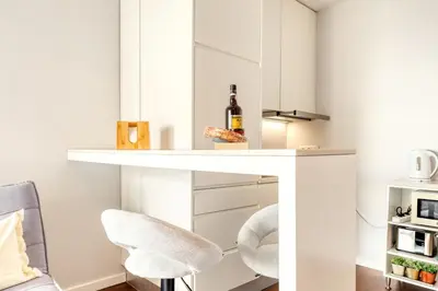 a white desk with two chairs and a bottle of wine at Elsa's Place, a Home in Madeira in Funchal