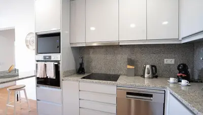 a kitchen with white cabinets and stainless steel appliances at Solar do Mar by LovelyStay in Funchal