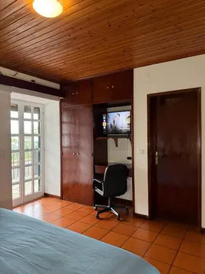 a bedroom with a bed and a chair and a television at Habitación con estacionamiento y baño privado in Funchal