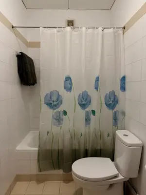 a bathroom with a toilet and a shower curtain with blue flowers at Habitación con estacionamiento y baño privado in Funchal