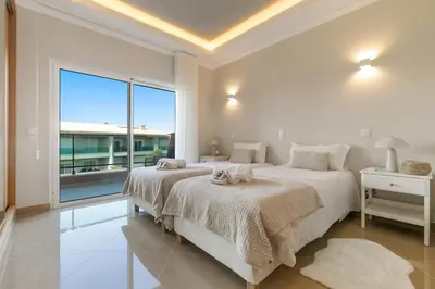 two beds in a white bedroom with a large window at Casa Eva, golfe, conforto, piscina e spa in Lagos