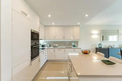 a kitchen with white cabinets and a table in it at Casa Eva, golfe, conforto, piscina e spa in Lagos