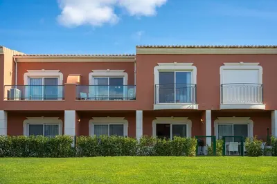 a red building with a green lawn in front of it at Casa Eva, golfe, conforto, piscina e spa in Lagos