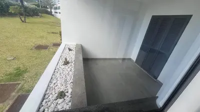a building with a window and a garden with rocks at Paradisus guest house in Caniço