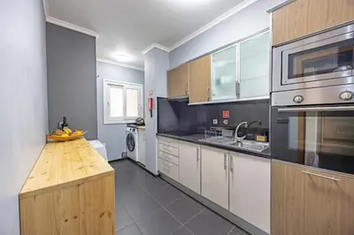 a kitchen with wooden cabinets and a counter top at Machico Apt Moderno Familias ou Grupos in Machico