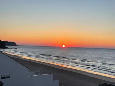 a sunset on a beach with the ocean at Casa Dourada - Golden Beach Apt in Budens