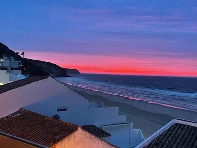 a sunset over a beach with buildings and the ocean at Casa Dourada - Golden Beach Apt in Budens