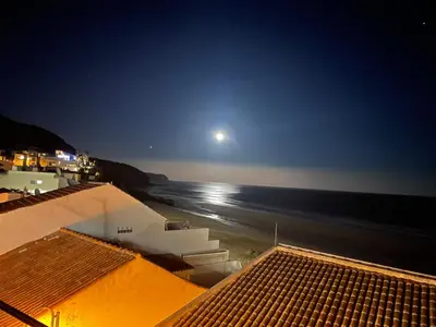 a view of the beach at night with the moon at Casa Dourada - Golden Beach Apt in Budens