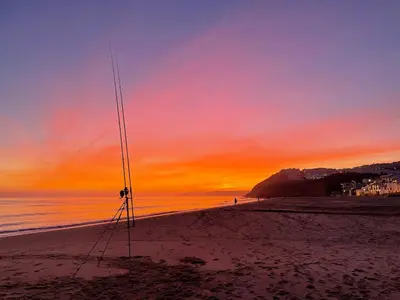 a sunset on a beach with a pole in the sand at Casa Dourada - Golden Beach Apt in Budens