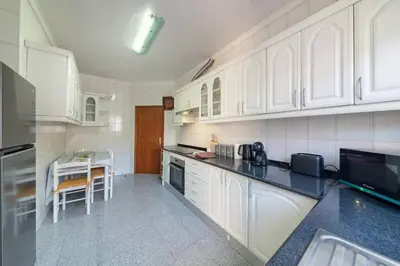 a kitchen with white cabinets and a table in it at Gorete Apartment by Mth in Funchal